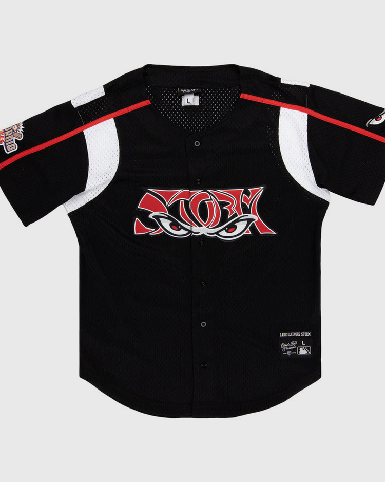 The Ebbets Field Lake Elsinore Storm MiLB Button Down Jersey is a black short-sleeve baseball jersey with white and red accents, mesh panels, a stylized eyes logo on the chest, and patches on the left sleeve and lower right front.