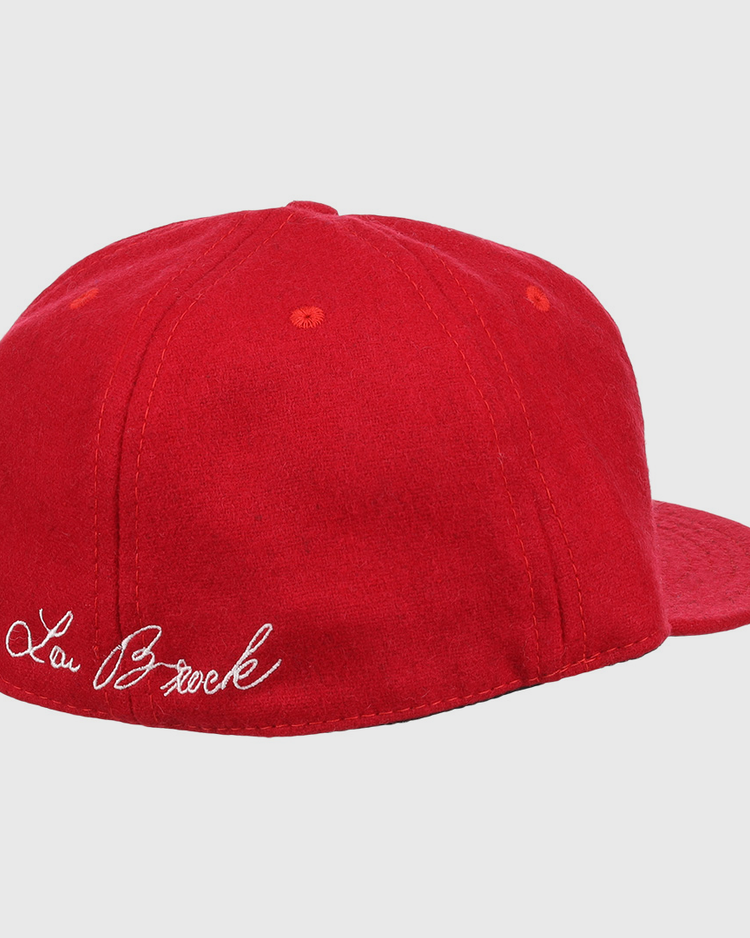 The Ebbets Field Flannels Lou Brock Signature Series Ballcap is a vintage red wool cap, shown from the back left, with Lou Brock’s signature in white cursive embroidered above the band.