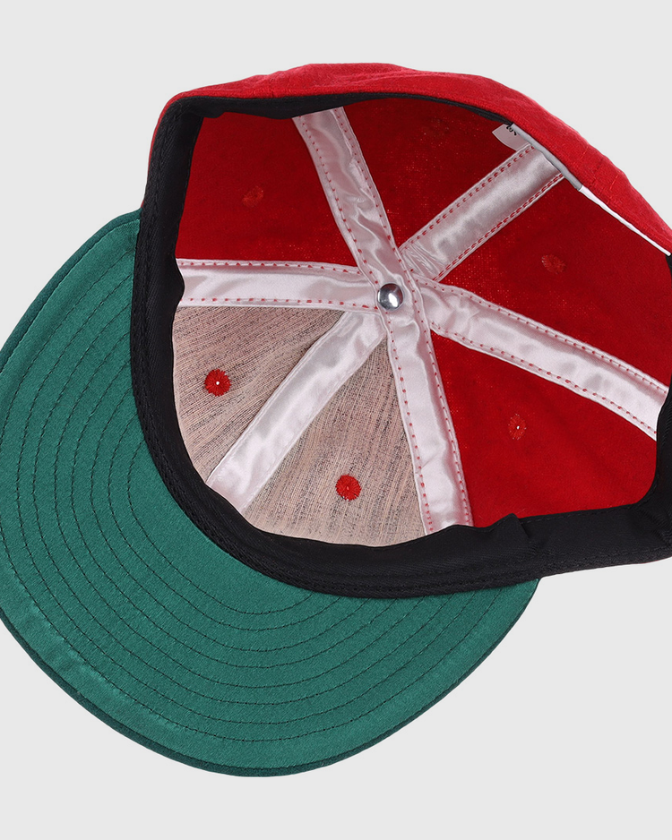 A top-down view of the EFF M&O Cigars 1946 Vintage Ballcap reveals white stitched panels, a green brim, red ventilation holes, and a silver center button.