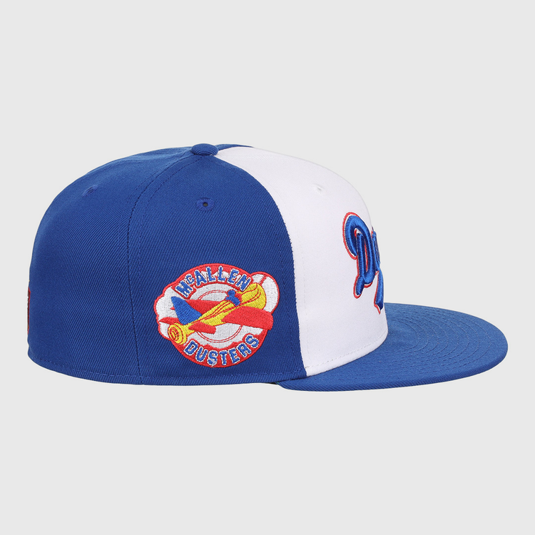 The EFF McAllen Dusters Lone Star Fitted Ballcap features blue and white panels, a flat blue brim, and a colorful yellow airplane patch with HEALEN DUSTERS embroidered, inspired by the classic Lone Star League team.