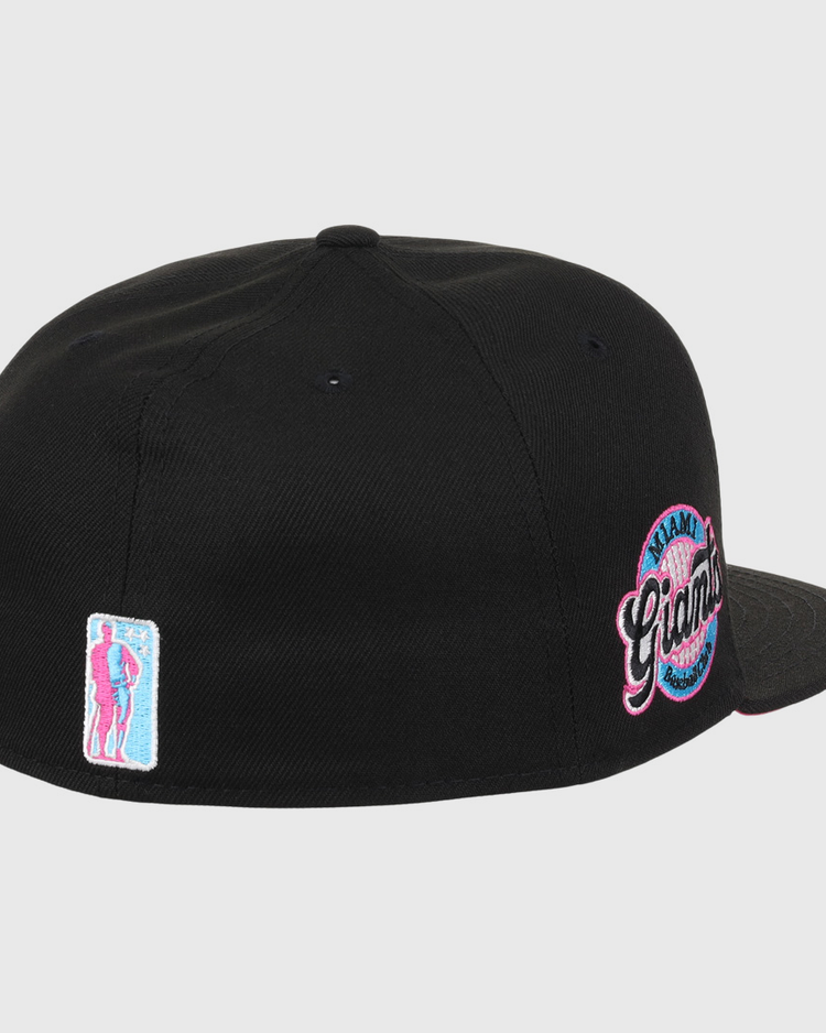 The EFF Miami Giants NLB Team Color Fitted Ballcap in black features a back view, an embroidered team logo patch, and a small pink and blue figure patch on the left, honoring this historic Black barnstorming team.