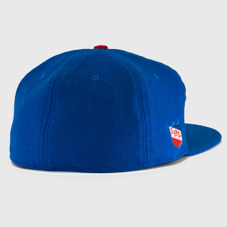 The EFF Milwaukee Clarks Vintage Ballcap is a royal blue wool hat with a red top button, viewed from the back, featuring a small red and white PH shield logo on the right side—a nod to classic goalkeeper caps.