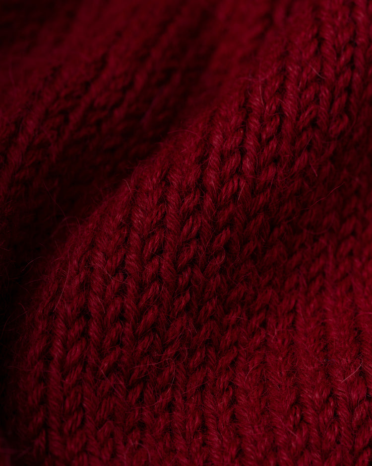 Close-up of the Philadelphia Phillies 1979 Wool Shawl Collar Sweater by Ebbets Field Flannels, featuring richly textured deep red knit with visible stitches and soft fibers, echoing classic MLB styles with gentle folds highlighting its quality.