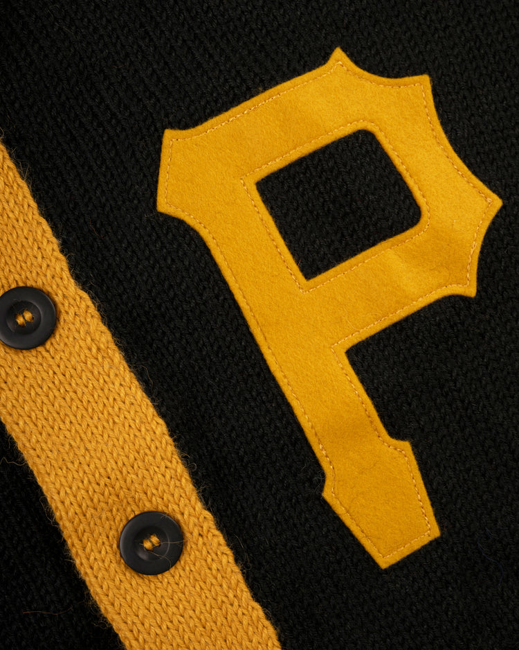 The Pittsburgh Pirates 1970 Wool Shawl Collar Sweater by Ebbets Field Flannels features black knit fabric, a large yellow P patch, yellow trim, and black buttons, echoing classic replica on-field baseball sweater design.