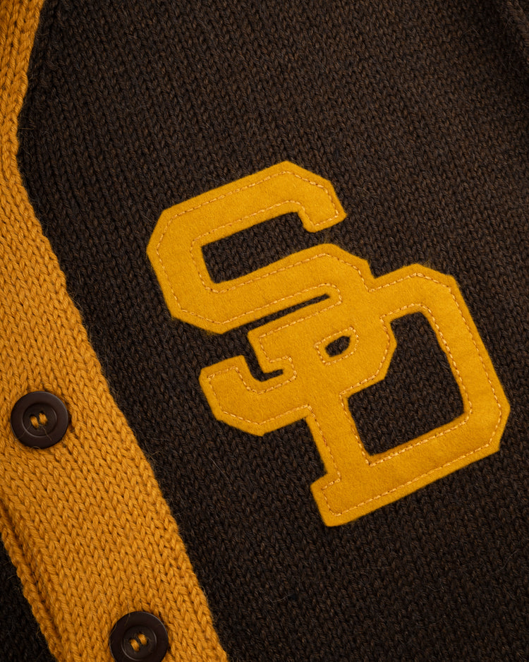 Close-up of the San Diego Padres 1969 Wool Shawl Collar Sweater by Ebbets Field Flannels, a dark brown knit with yellow trim, buttons, and large S and D letters, inspired by classic Padres on-field baseball sweaters.