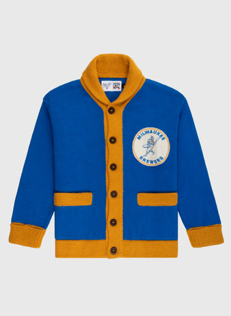 The Ebbets Field Flannels Milwaukee Brewers 1970-1977 Wool Shawl Collar Sweater features blue and gold colors, brown buttons, gold trim, and a chest patch reading MILWAUKEE BREWERS with a baseball player graphic.