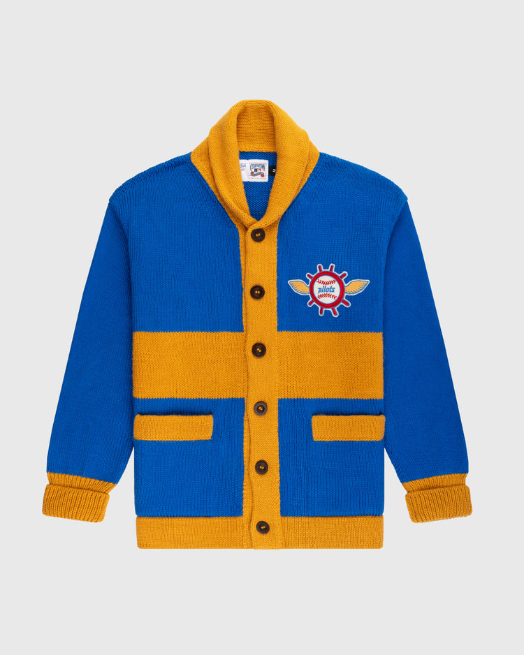The Seattle Pilots 1969 Wool Shawl Collar Sweater by Ebbets Field Flannels is a blue and yellow knit cardigan inspired by vintage baseball, with brown buttons, two front pockets, and a chest patch featuring a winged red gear with hotel text.
