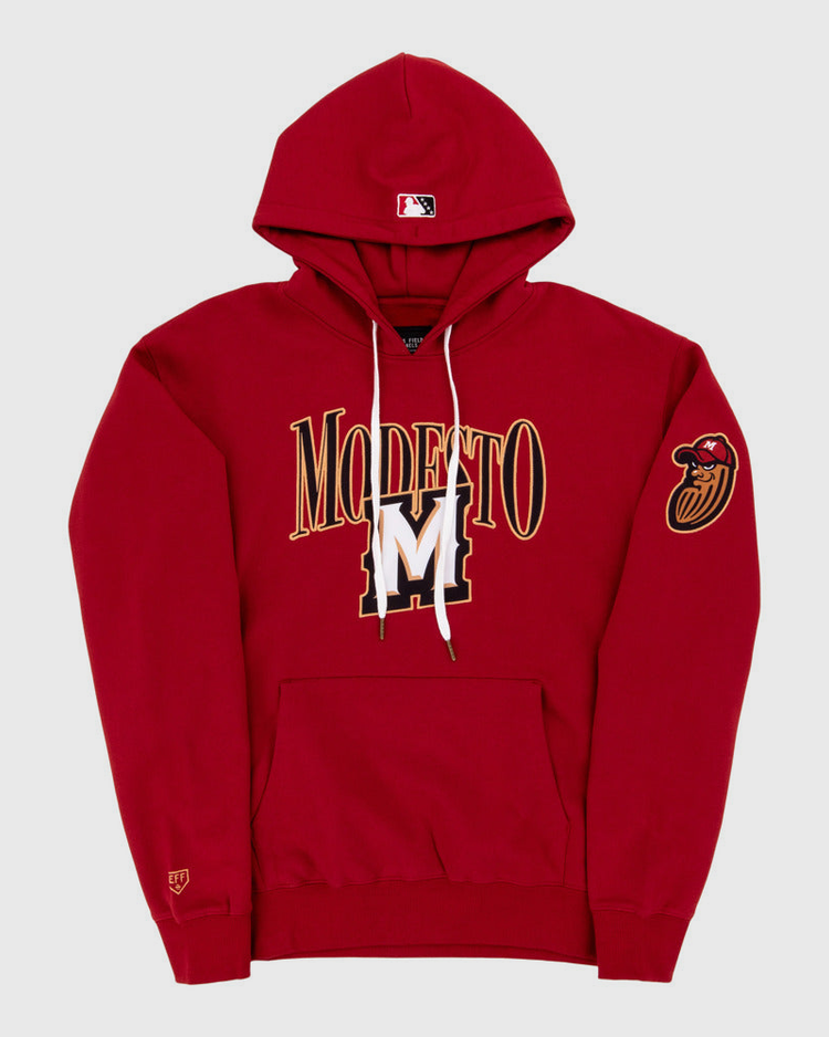 The Ebbets Field Modesto Nuts MiLB Cotton Hooded Sweatshirt is a red hoodie with MODESTO and a large gold and white M on the front, a red bird head patch on the left sleeve, and an MLB logo on the hood.