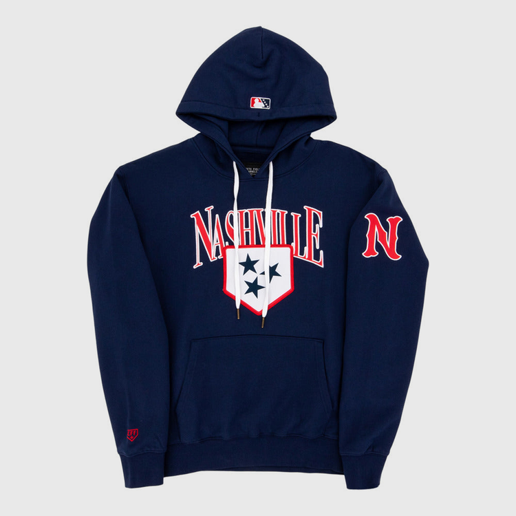 The Ebbets Field Nashville Sounds MiLB Cotton Hooded Sweatshirt is a navy blue hoodie with white drawstrings, Nashville in bold white and red letters, a three-star shield on the chest, red N on the sleeve, and an MLB logo on the hood.