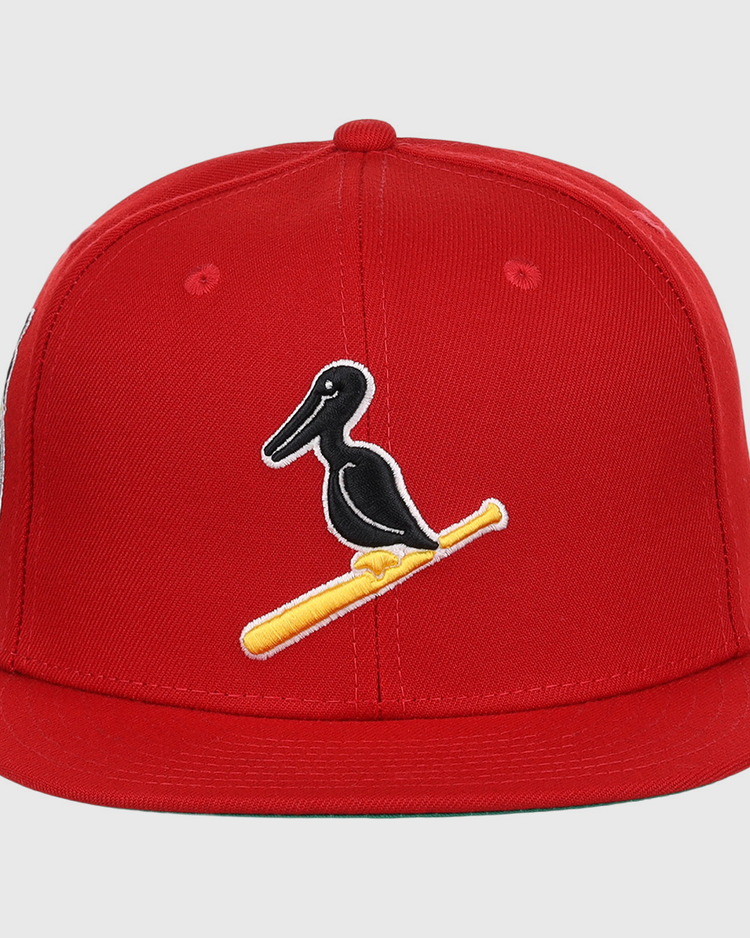 The EFF New Orleans Black Pelicans NLB Team Color Fitted Ballcap in red features an embroidered black pelican on a yellow bat, honoring the historic Negro Southern League team.