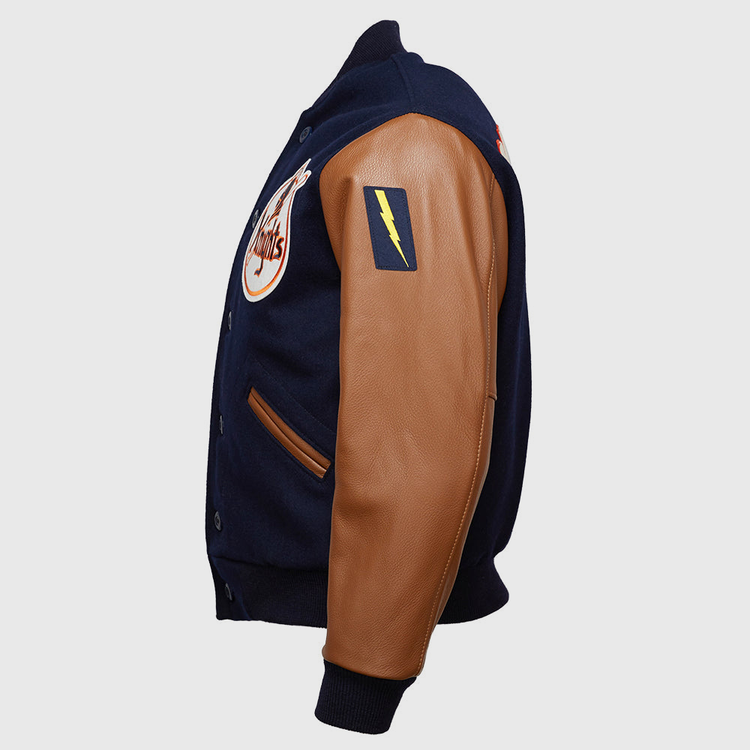 The EFF New York Knights 1939 Authentic Jacket is a navy melton wool varsity jacket with tan leather sleeves, a yellow lightning bolt patch on the upper arm, and a circular chest logo, shown from a side angle.