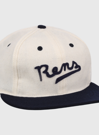 The New York Rens Wool Ballcap by Ebbets Field Flannels is a vintage-style white cap with a navy brim and Rens embroidered in script, celebrating Black basketball history and the legacy of the legendary team.