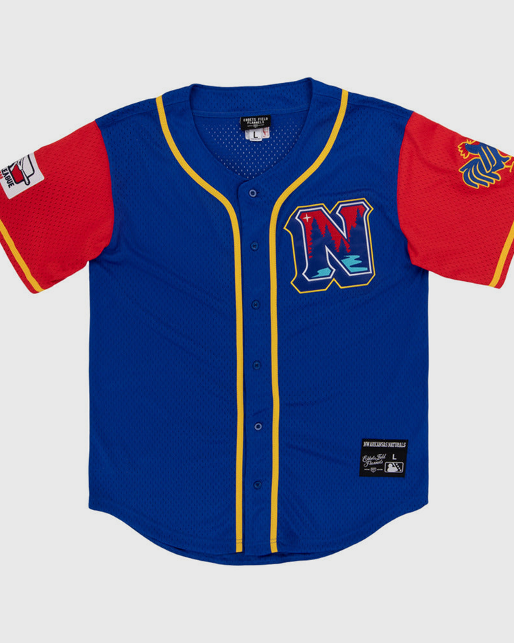 The Ebbets Field Northwest Arkansas Naturals MiLB Button Down Jersey features blue fabric, yellow trim, red sleeves, a left-sleeve patch, lion logo on the right sleeve, and a chest 