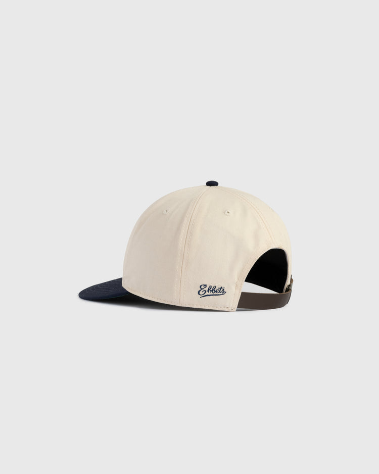 The Ebbets Field New York Black Yankees Felt NY Cotton Twill Ballcap features a beige cotton twill body, navy blue brim, brown adjustable strap, and embroidered Ebbets logo at the back. Shown from behind on a plain light gray background.