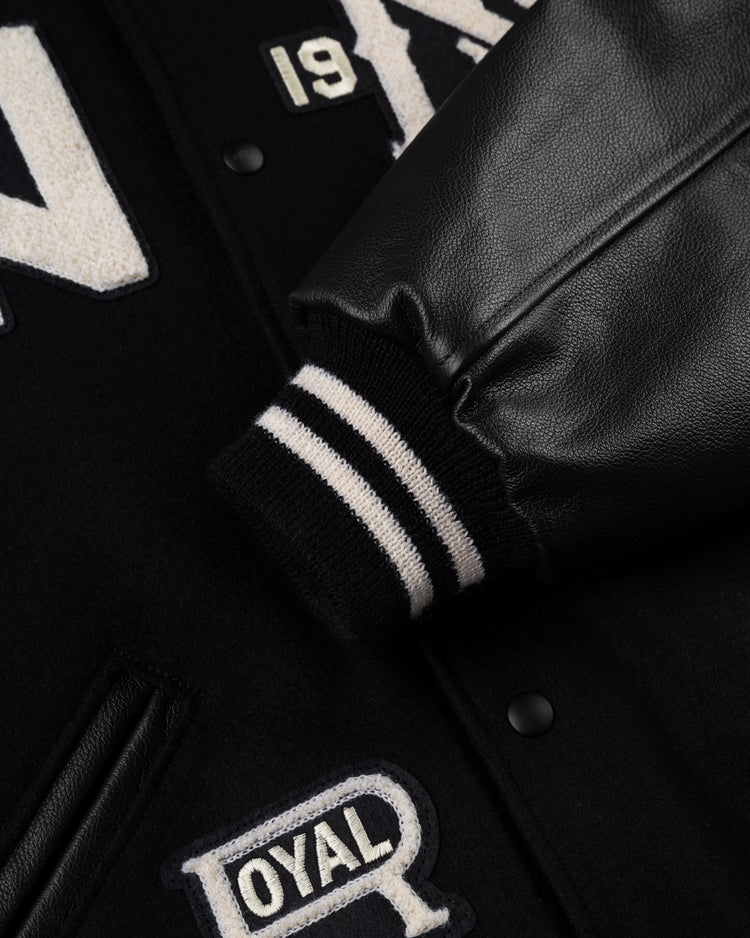 Close-up of the Ebbets Field Negro League Wool & Leather Varsity Jacket sleeve, featuring black-and-white striped ribbed cuff, leather arm, and embroidered white ROYAL lettering with a 19 patch.