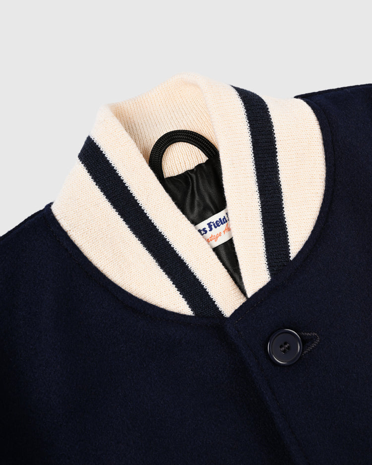 Close-up of the EFF New York Black Yankees 1940 Authentic Wool & Leather Varsity Jacket in navy, featuring a cream ribbed collar with dark stripes and a visible inner label on a black hanger.