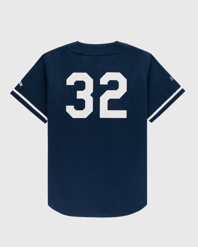 The Ebbets Field New York Black Yankees Cotton Twill Baseball Jersey features navy blue fabric, white sleeve stripes, and a bold number 32 on the back, inspired by Negro Leagues baseball. Background is plain light gray.