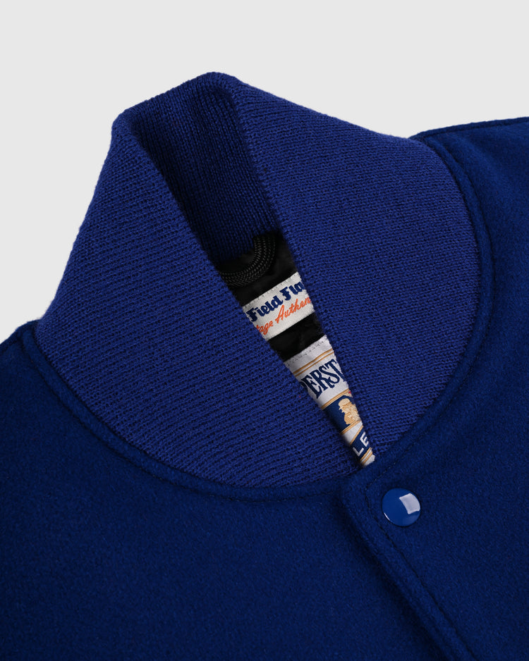 Close-up of the EFF New York Mets 1969 Authentic All Wool Varsity Jacket’s royal blue ribbed collar and snap button, with a partially visible inside tag displaying text and graphics.