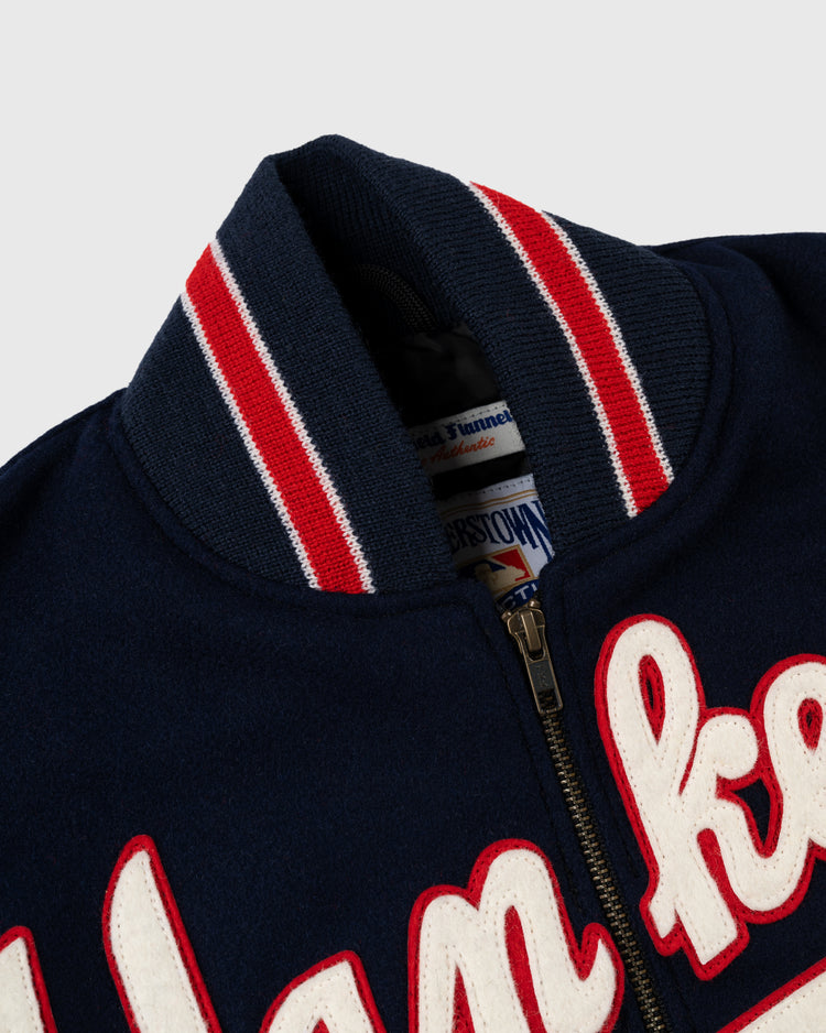 Close-up of the EFF New York Yankees 1947 Authentic All Wool Varsity Jacket, showing its navy color, red and white striped ribbed collar, zipper, white cursive front embroidery, and partially visible inner label—honoring the 1947 World Champions.