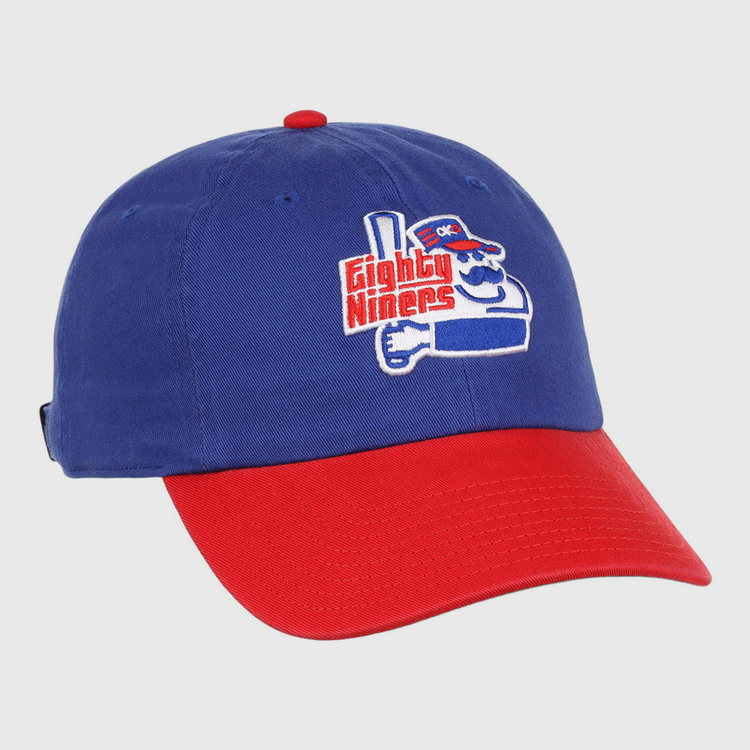 The Ebbets Field Oklahoma City 89Ers MiLB Logo Dad Ballcap is blue with a red brim, featuring an embroidered cartoon character holding a bat and “Eighty Niners” text on the front.
