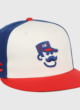 The Ebbets Field Oklahoma City 89Ers MiLB Snapback Ballcap features a white front, blue back, red brim, and a cartoon face with a blue cap embroidered with 