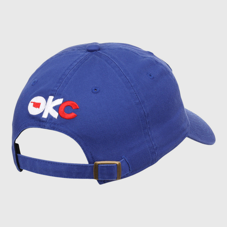 The Ebbets Field Oklahoma City Dodgers MiLB Dad Ballcap is blue, features OKC embroidered on the back in white and red with an Oklahoma outline in the O, and has an adjustable brass-buckle strap.