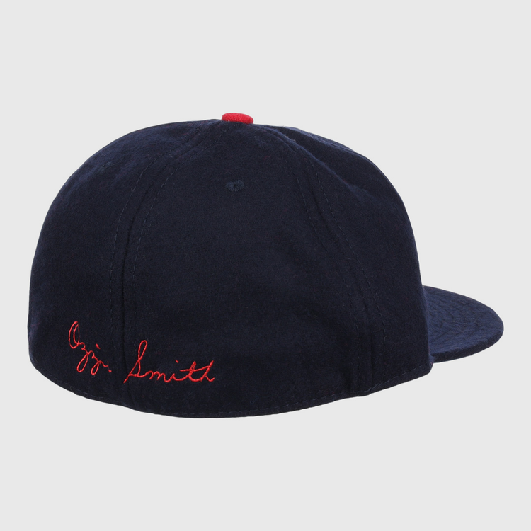 The Ozzie Smith Signature Series Ballcap by Ebbets Field Flannels is shown from the rear, featuring navy vintage wool, red Ozzie Smith stitching on the back, and a small red button on top.