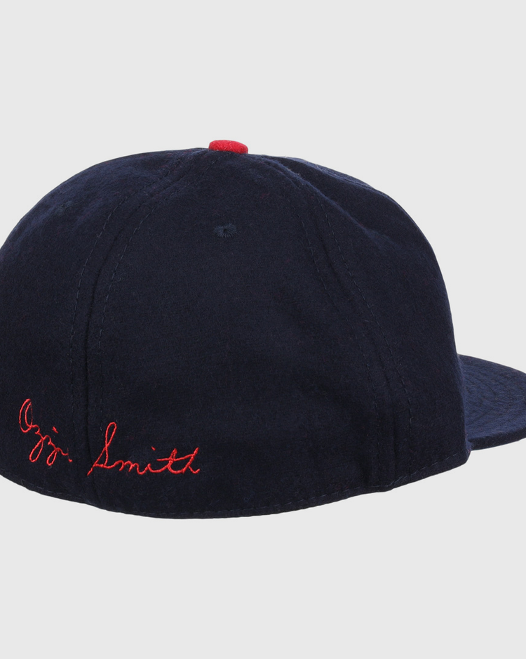 The Ozzie Smith Signature Series Ballcap by Ebbets Field Flannels is shown from the rear, featuring navy vintage wool, red Ozzie Smith stitching on the back, and a small red button on top.