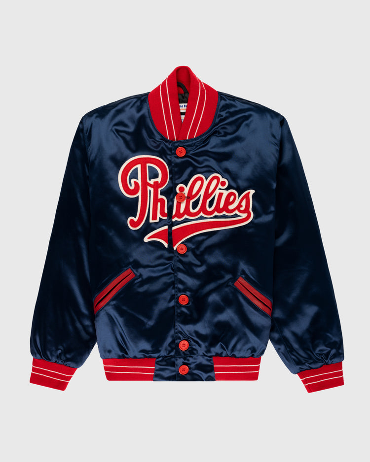 The EFF Philadelphia Phillies 1937 Authentic All Satin Varsity Jacket features navy blue satin with red and white striped cuffs, collar, and hem, and “Phillies” boldly embroidered across the chest, inspired by the Baker Bowl era.