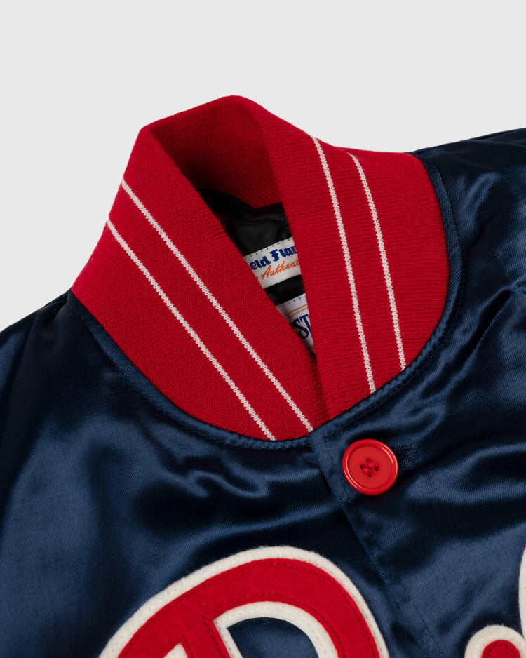 Close-up of the EFF Philadelphia Phillies 1937 Authentic All Satin Varsity Jacket, featuring blue satin, a red and white striped ribbed collar, red button, white embroidered lettering, and a visible inside label inspired by the Baker Bowl era.