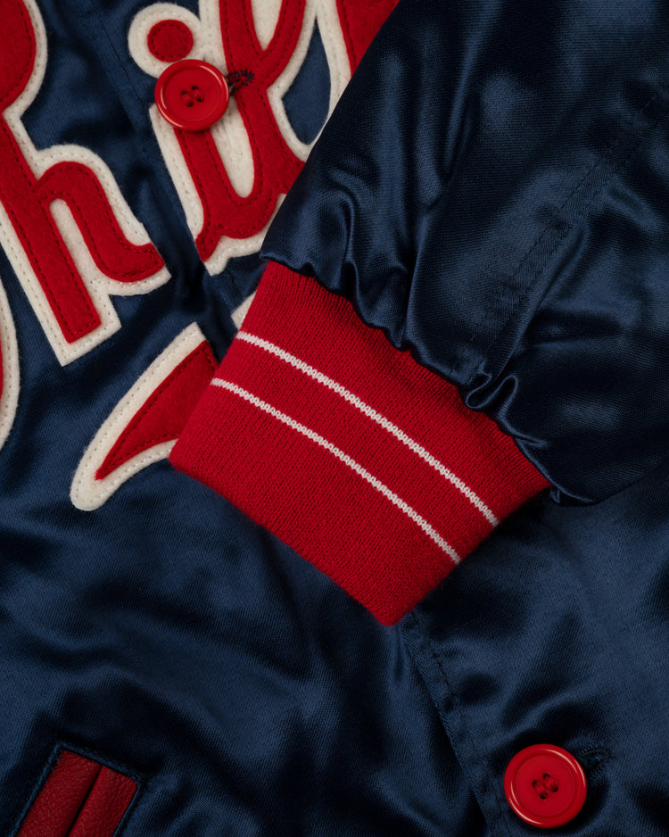 Close-up of the EFF Philadelphia Phillies 1937 Authentic All Satin Varsity Jacket in navy with red buttons, a red-and-white striped knit cuff, and red-and-white embroidered script inspired by the 1937 team at Baker Bowl.