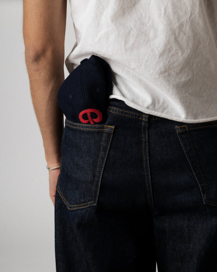 A person in a white t-shirt and dark jeans has an EFF Philadelphia Stars 1940 Authentic Wool Softbrim Ballcap tucked into their back pocket.