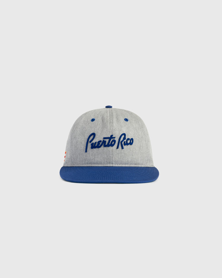 The Ebbets Field Puerto Rico 1958 National Team Cotton Twill Ballcap features a gray crown, blue brim, and Puerto Rico in blue script, inspired by the iconic Caribbean Series style. Shown against a simple light background.