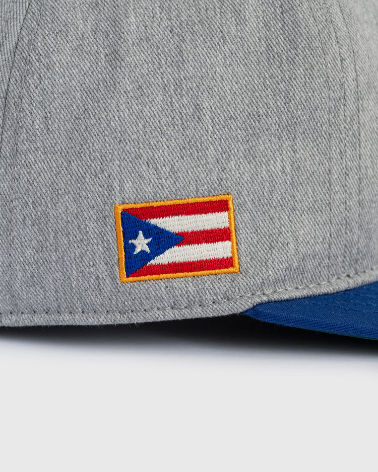 A close-up of the Ebbets Field Puerto Rico 1958 National Team Cotton Twill Ballcap, showing a small embroidered Puerto Rican flag patch and the blue brim’s edge.