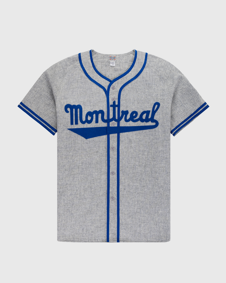 The Ebbets Field Montreal Royals 1946 Authentic Wool Road Baseball Jersey features heather gray wool, blue trim, Montreal script on the chest, a button-down front, and short sleeves—replicating Jackie Robinson’s iconic road jersey.
