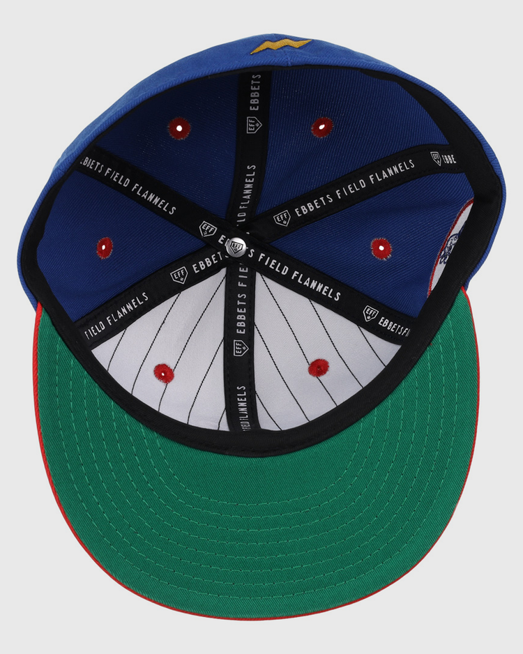 The Reddy Kilowatt EFF DNA Fitted Ballcap by EFF features a blue crown, green undervisor, red trim, black Ebbets Field Flannels branding inside, and a white pinstriped lining with red stitching.