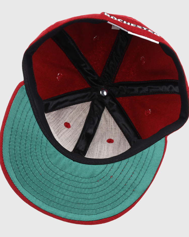 An overhead look at the Rochester Red Wings Letterhead Wool Vintage Ballcap by EFF shows the red caps green underbrim, black seam lining, and part of ROCHESTER visible on the inner label.