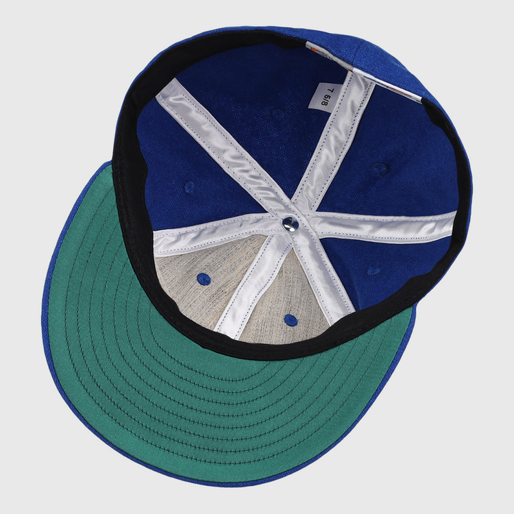 The image shows the inside view of an EFF Royal Ponciana Giants 1912 Vintage Ballcap in blue wool with a green brim, size tag 7 1/8, white and black lining, exposed stitching, and classic hotel league baseball styling.