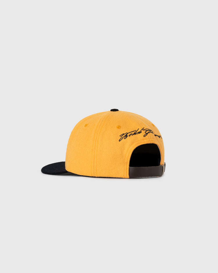 The Roberto Clemente 1972 Signature Series Wool Ballcap by Ebbets Field Flannels features a yellow crown, black brim, adjustable brown strap, and black cursive embroidery—ideal for Pittsburgh Pirates fans. Shown on a plain light gray background.