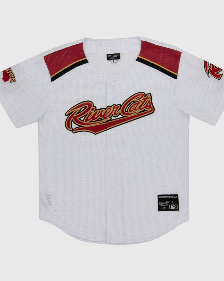 The Ebbets Field Sacramento River Cats MiLB Button Down Jersey is white with red and black accents, features the team logo across the chest, a left sleeve patch, black collar tag, and an official patch near the bottom hem.