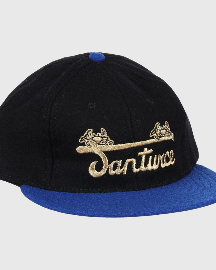 The EFF Santurce Cangrejeros Gilded Collection Ballcap features a black crown, blue brim, gold scroll details, and Santwoz gold script embroidery—a striking nod to the Puerto Rico League.