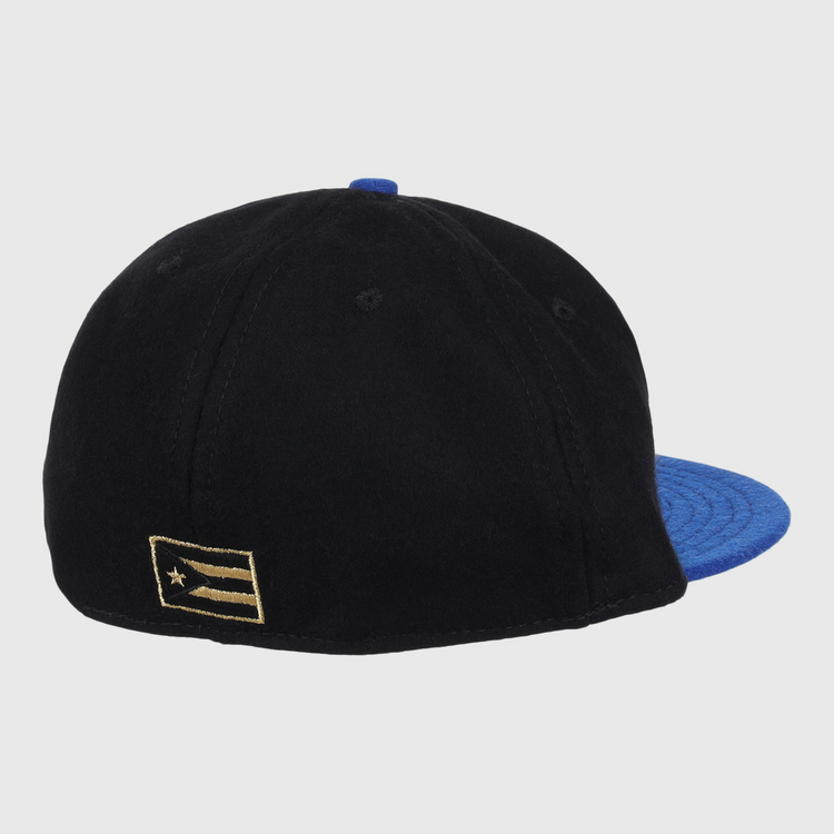 The EFF Santurce Cangrejeros Gilded Collection Ballcap in black features a blue brim and a gold-and-black flag patch on the left side, seen from the back—a stylish tribute to Puerto Rico League heritage.