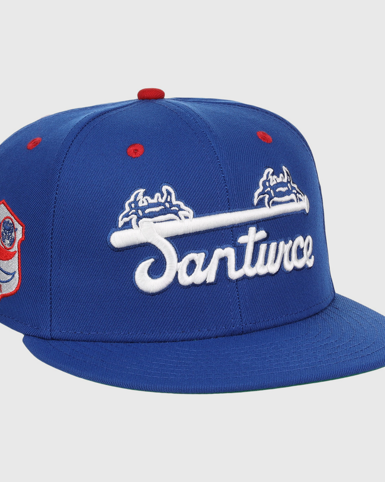 The EFF Santurce Cangrejeros NLB Team Color Fitted Ballcap is a vintage-inspired blue hat with Santurce in white under two blue and white crab logos, plus a Puerto Rican League red and white side patch and red accents on the top and eyelets.