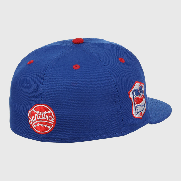 The EFF Santurce Cangrejeros NLB Team Color Fitted Ballcap is a vintage-inspired blue cap with red accents, featuring two embroidered patches: a round red Santurce logo and a shield patch with a flag and number 21 from the Puerto Rican League.