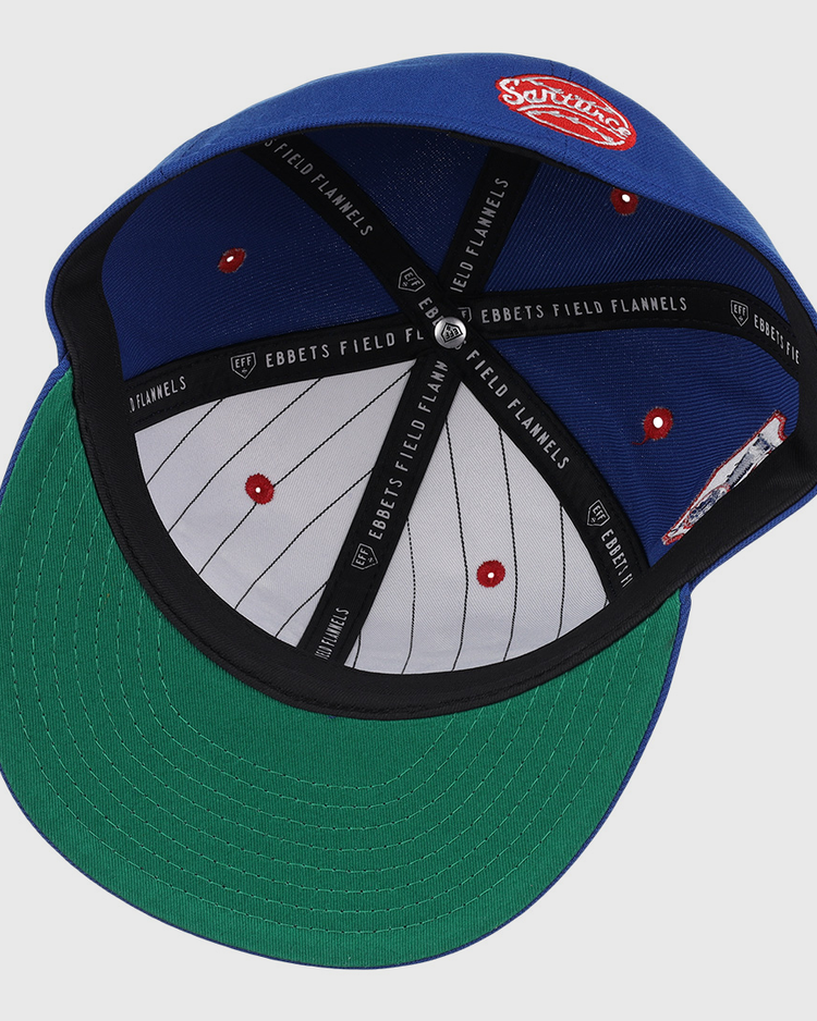 The Santurce Cangrejeros NLB Team Color Fitted Ballcap by EFF features a blue vintage-inspired design, green undervisor, gray crown with red eyelets, black EBBETS FIELD FLANNELS taping, and a red-and-white patch on top.