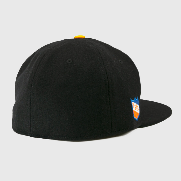 The EFF St. Paul Fighting Saints 1961 Vintage Ballcap is a black wool cap with a yellow top button, blue and orange shield logo on the right side, and classic styling inspired by the Saints hockey team.