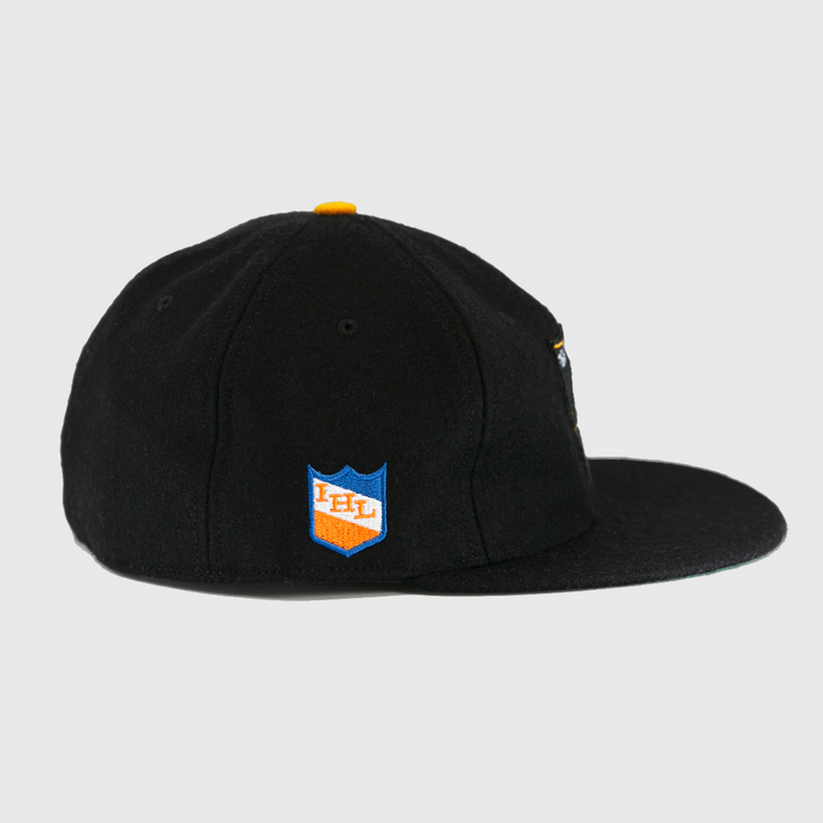 The EFF St. Paul Fighting Saints 1961 Vintage Ballcap is a black wool cap with a flat brim, yellow top button, and a blue and orange shield patch on the side featuring IHL in white.