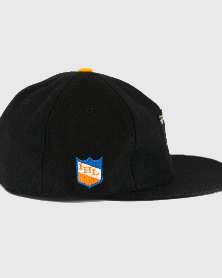 The EFF St. Paul Fighting Saints 1961 Vintage Ballcap is a black wool cap with a flat brim, yellow top button, and a blue and orange shield patch on the side featuring IHL in white.