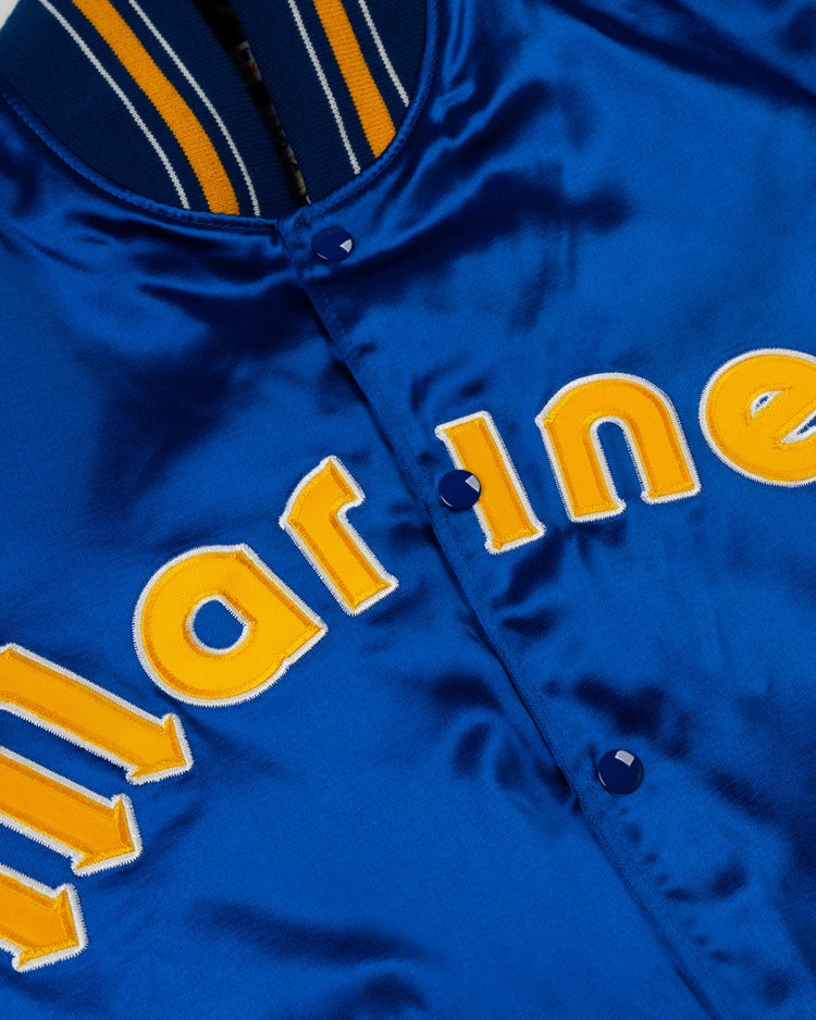 A close-up of the EFF Seattle Mariners 1982 Authentic All Satin Varsity Jacket: shiny blue satin with yellow and white “marine” lettering, blue buttons, and a yellow-and-white striped collar.