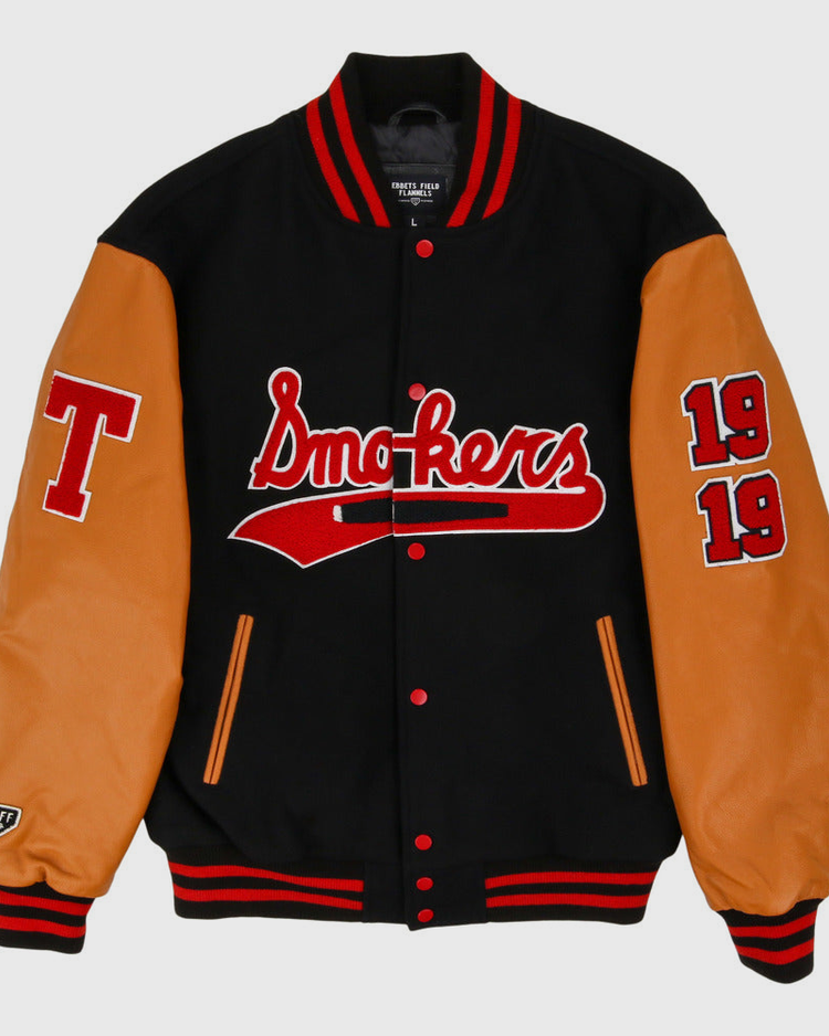 The Ebbets Field Tampa Smokers MiLB DNA Varsity Jacket features a black body, tan leather sleeves, red/white striped cuffs, 